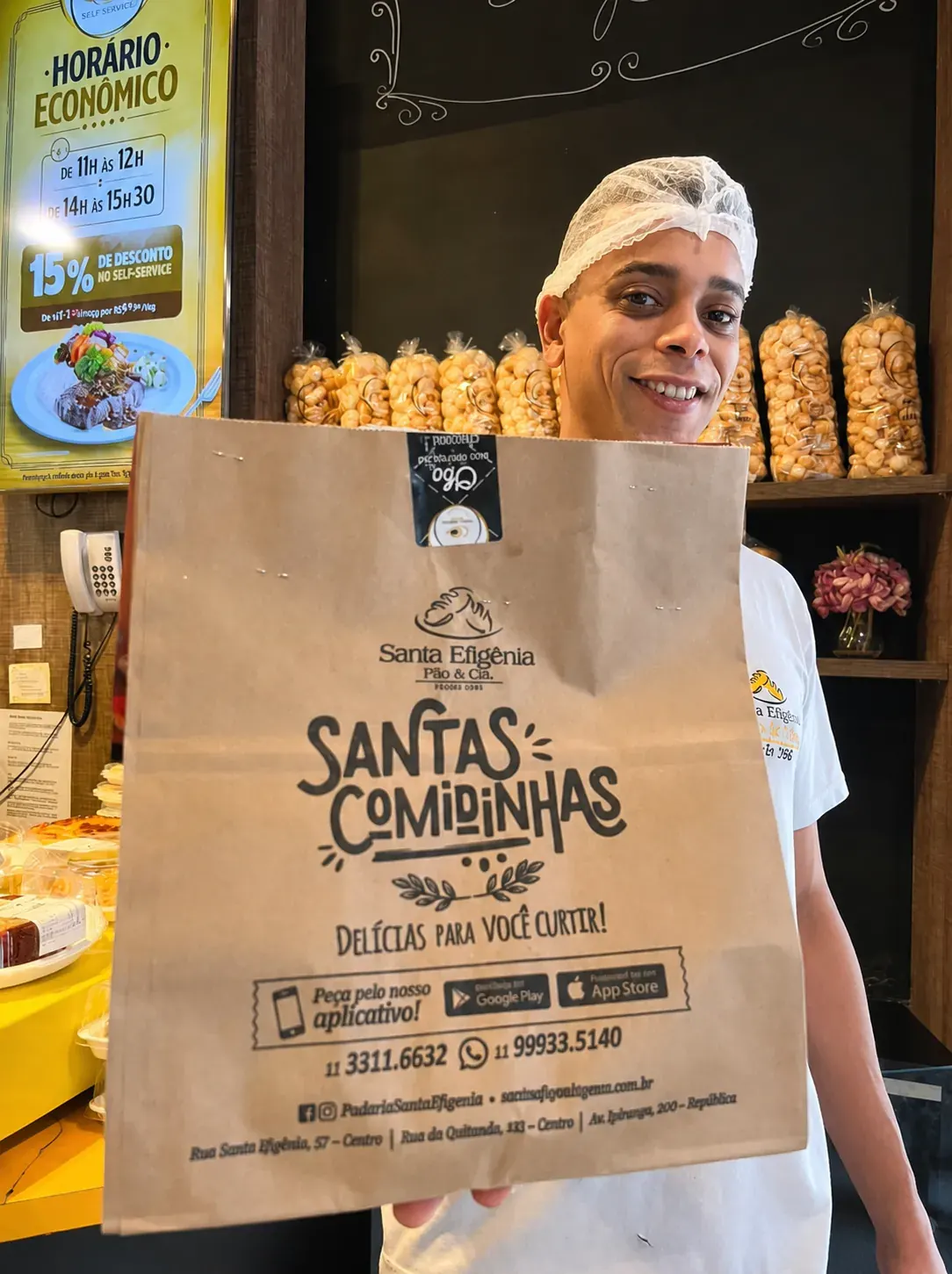 Profissional da Santa Efigênia apresentando uma embalagem da padaria